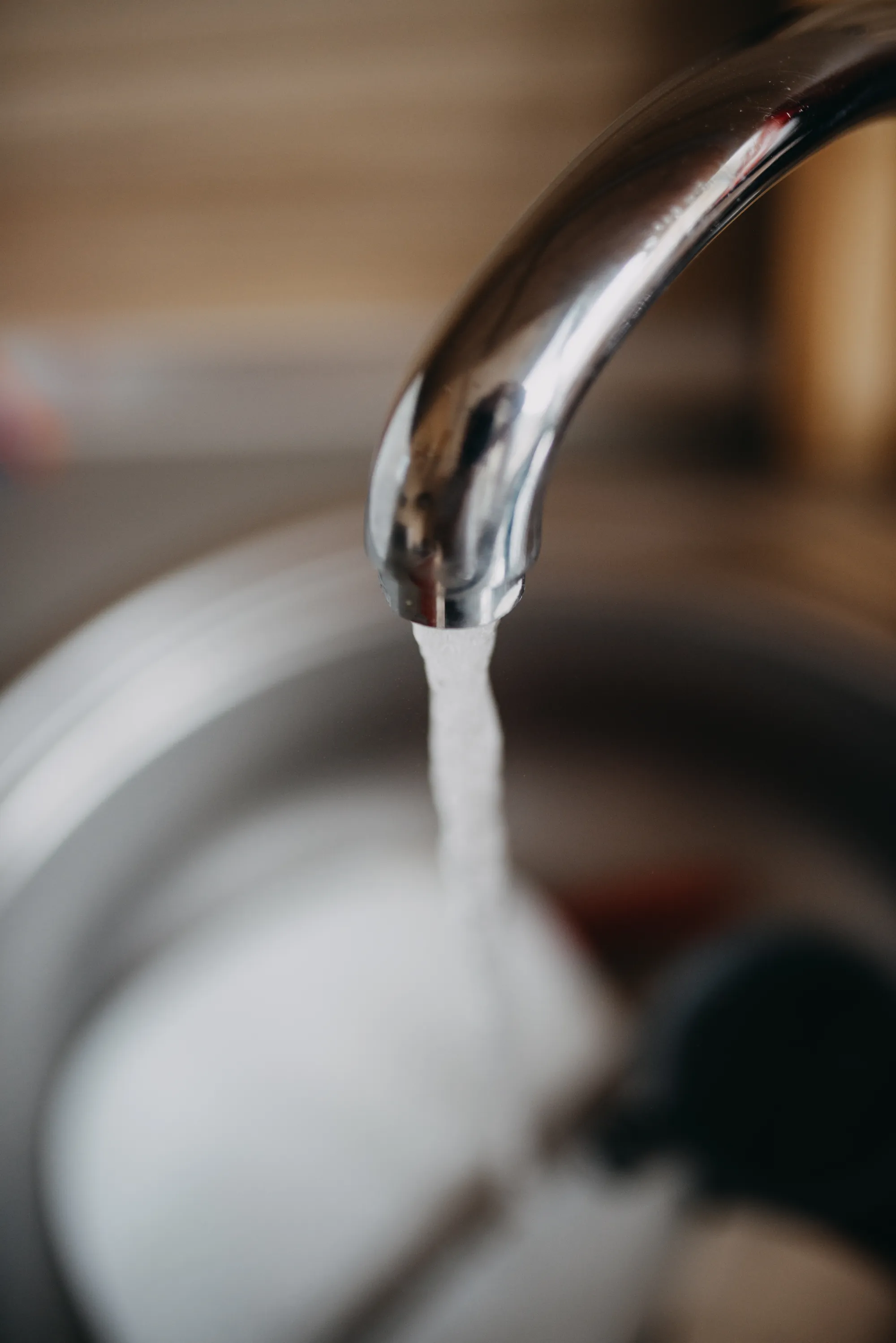 Chorro de agua sale de un grifo cromado de cocina hacia un fregadero metálico