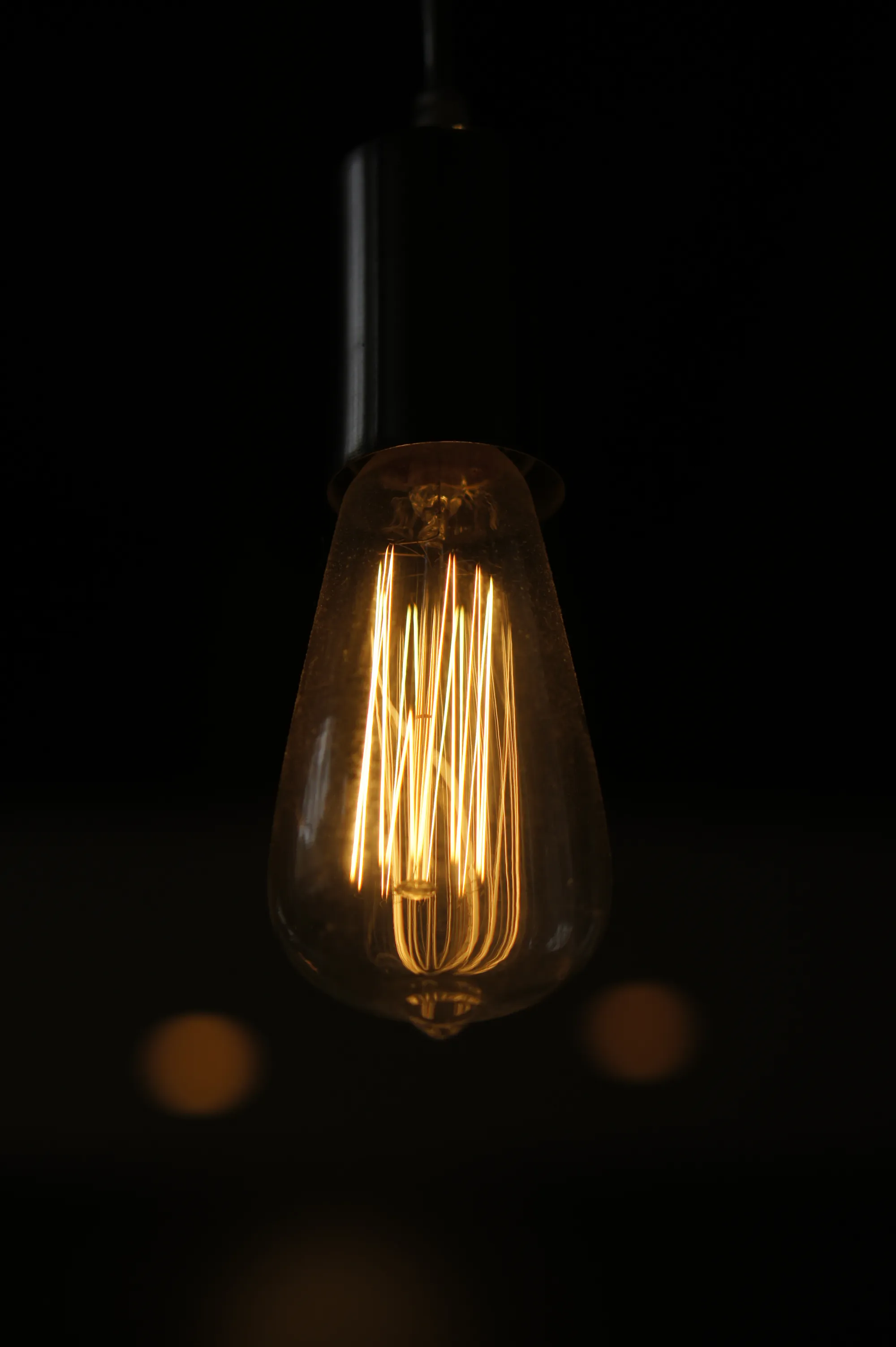 Bombilla de filamento tipo Edison encendida, colgada en una habitación a oscuras