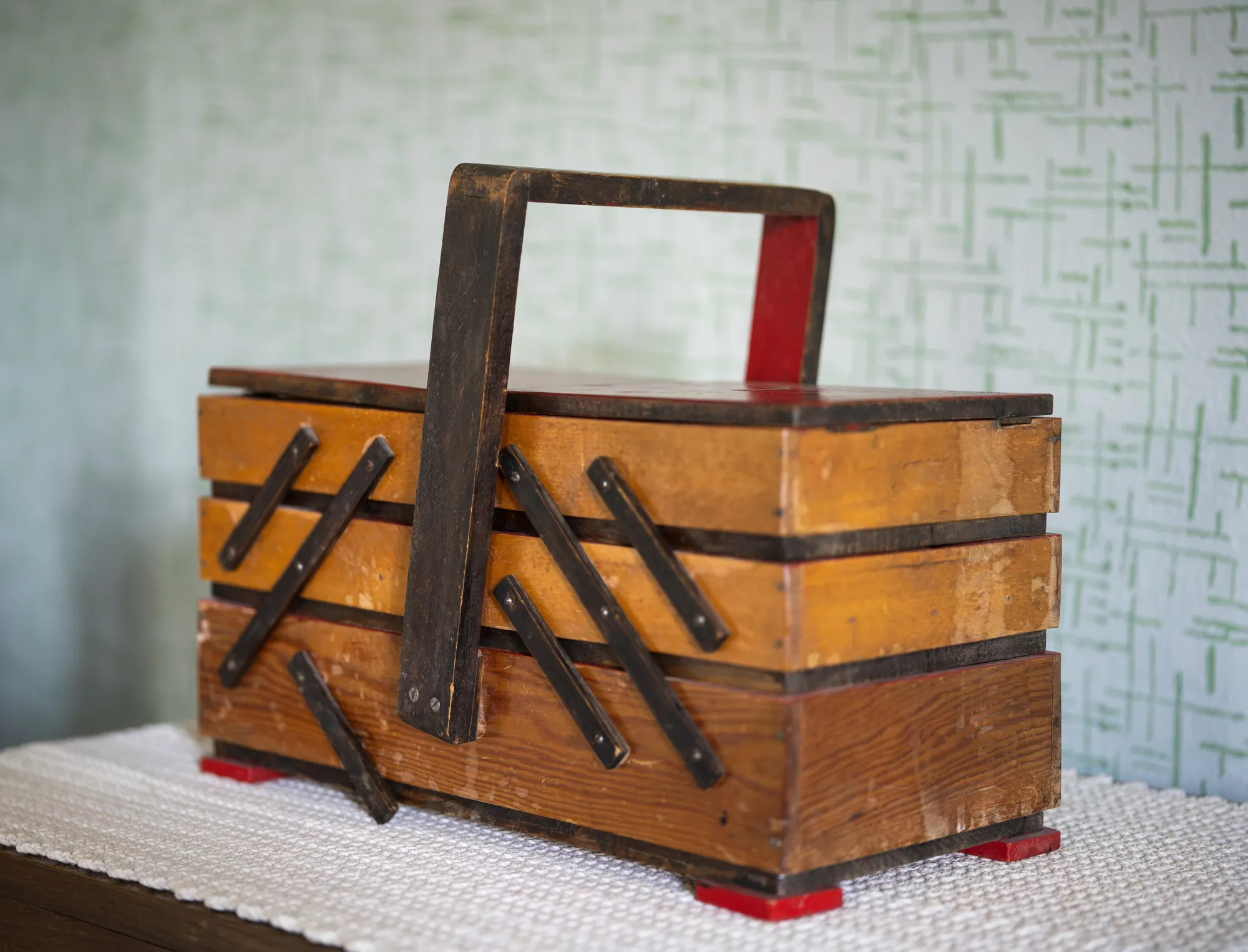 Caja de herramientas de madera antigua con asa, sobre un tapete de ganchillo