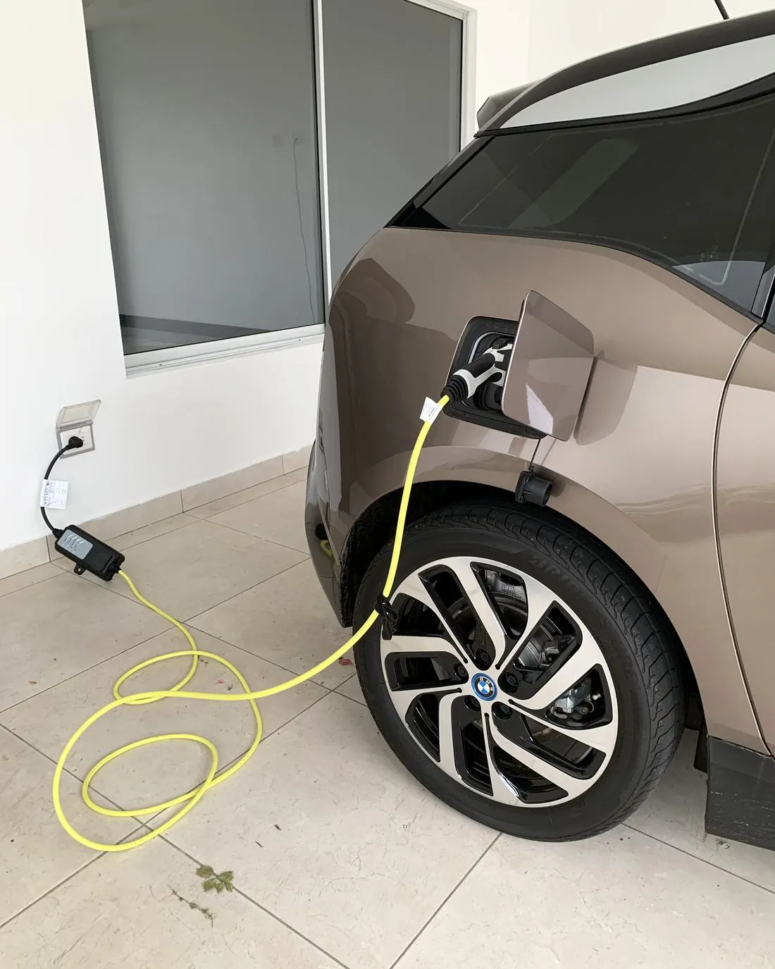 Lateral de un coche eléctrico con el cable de carga conectado a una toma de pared