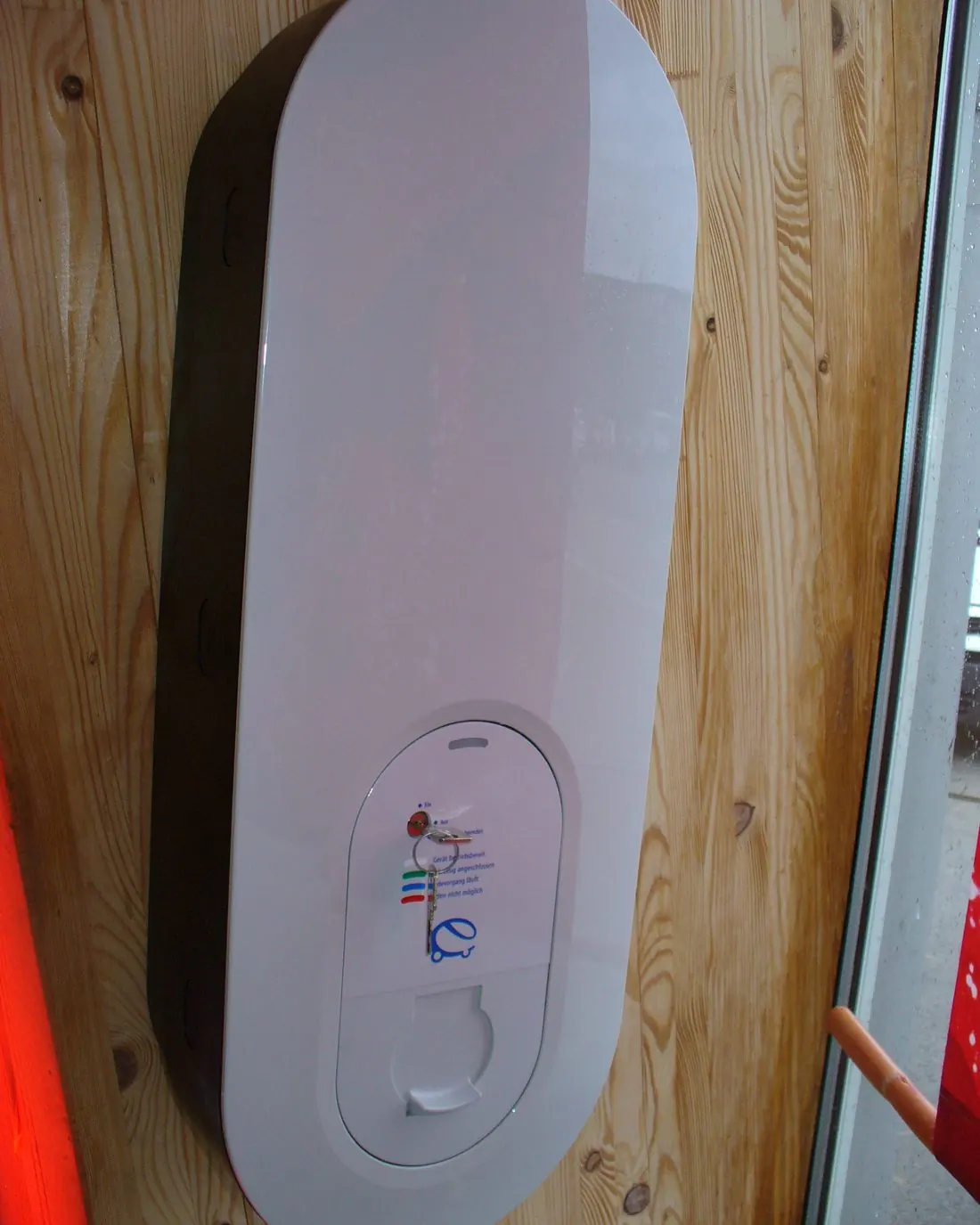 Cargador de coche eléctrico blanco atornillado a una pared revestida de madera