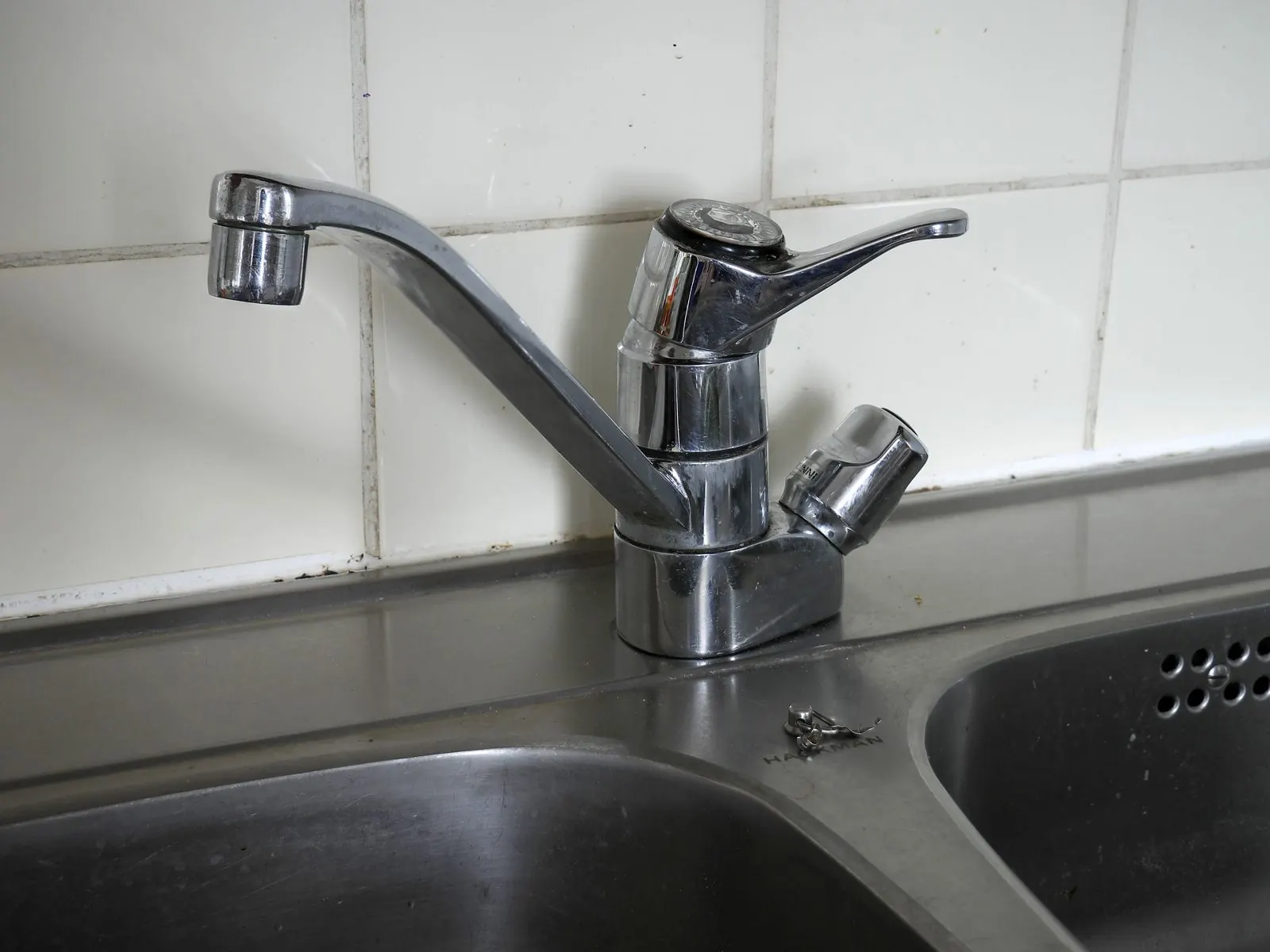 Grifo monomando de cocina cromado instalado sobre un fregadero doble de acero