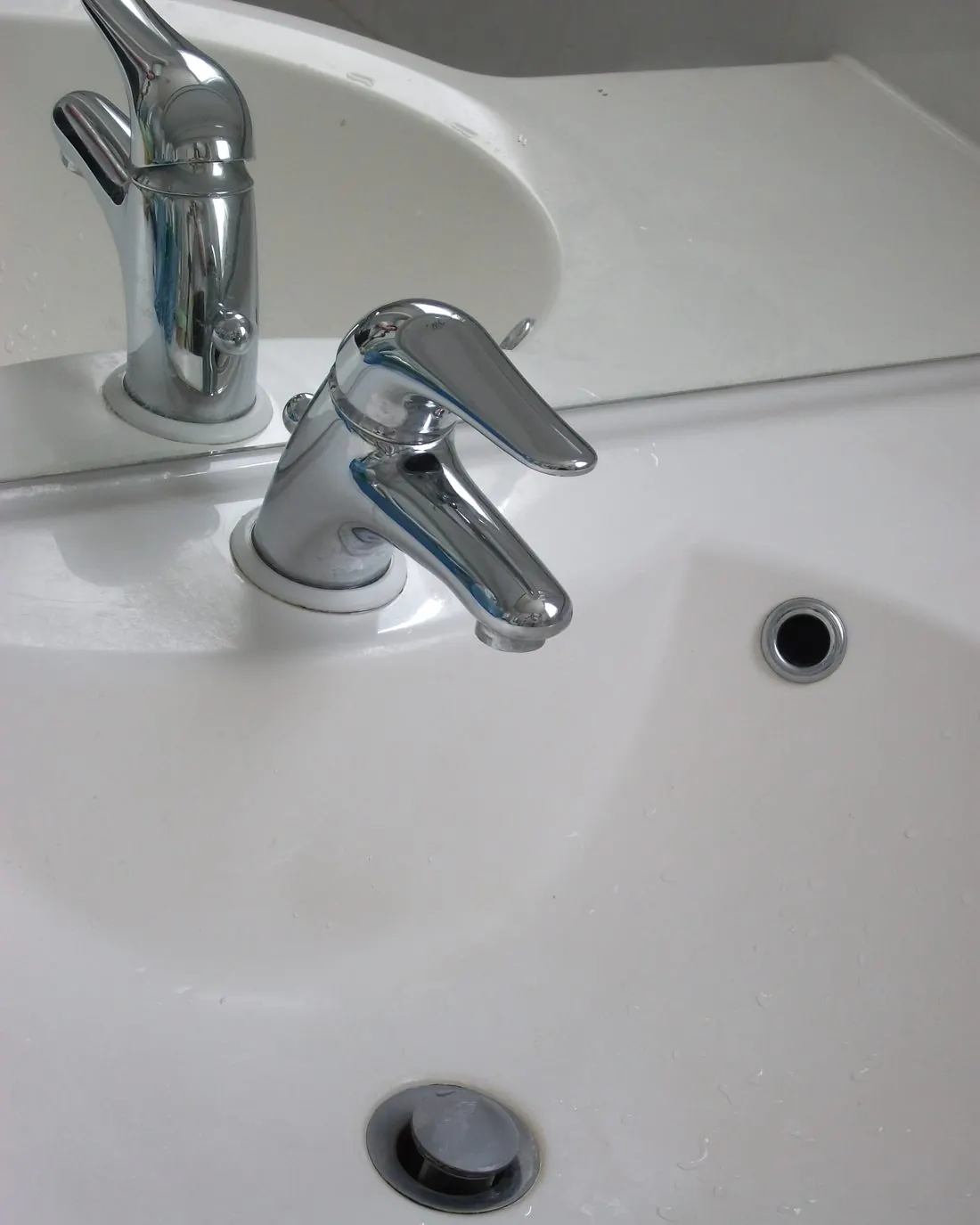 Grifo monomando cromado de lavabo sobre un lavamanos blanco con rebosadero