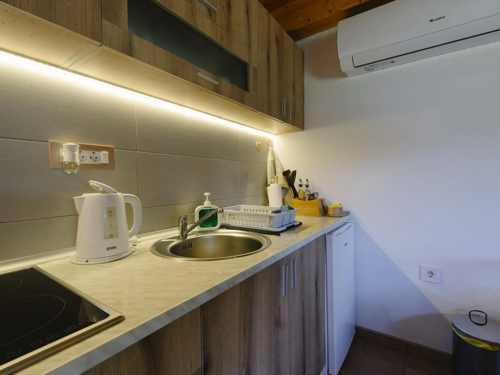Cocina pequeña con tira LED bajo los muebles altos iluminando la encimera