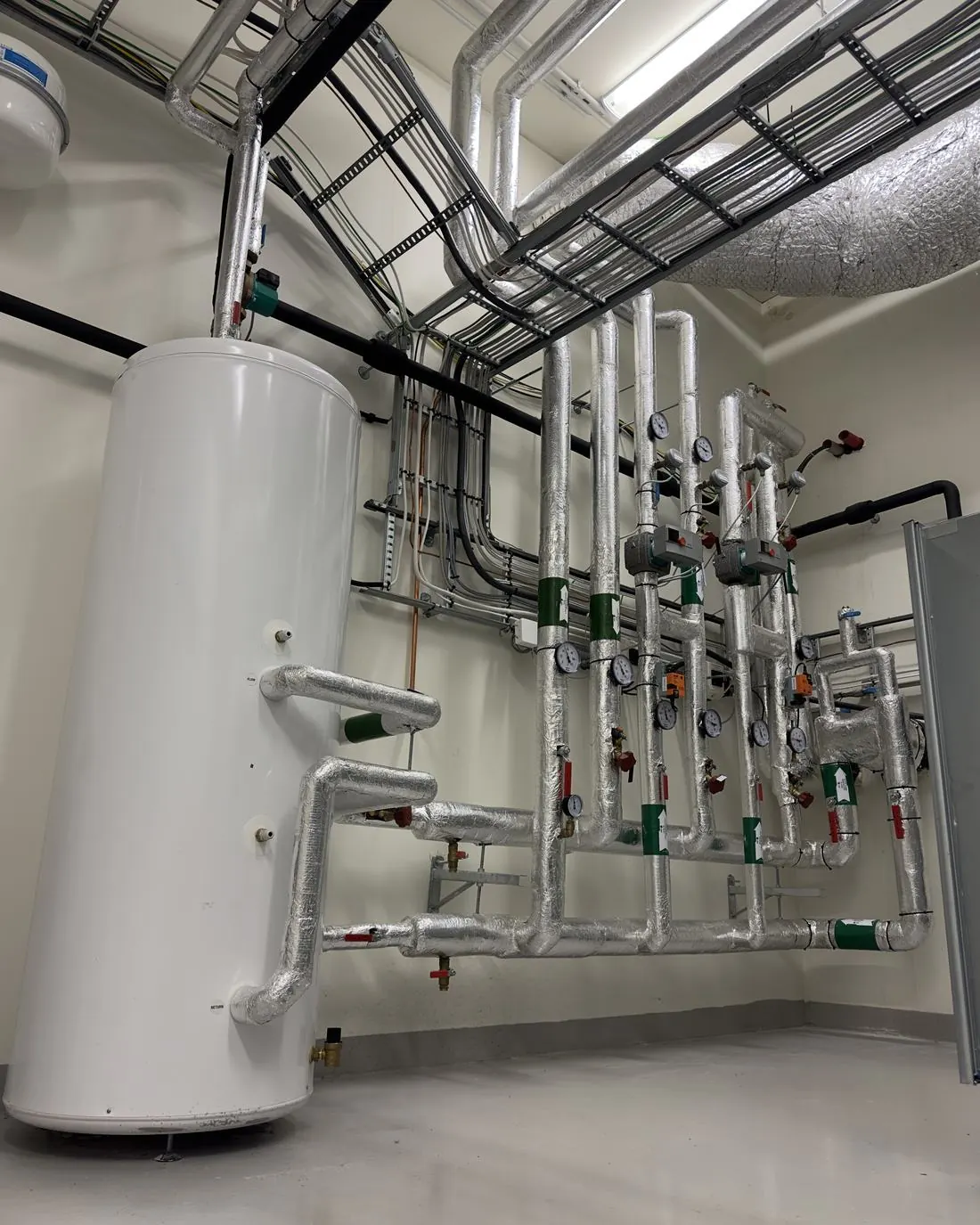 Cuarto técnico con depósito de agua caliente, tuberías aisladas y válvulas